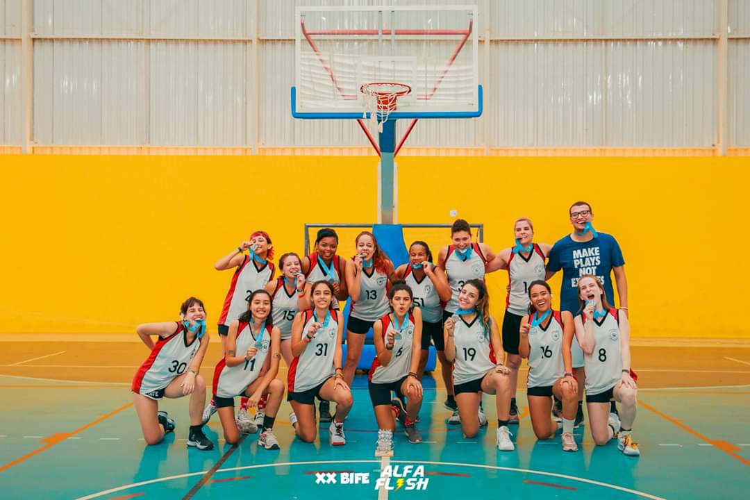 Foto do time feminino do IME ganhando, mordendo suas medalhas